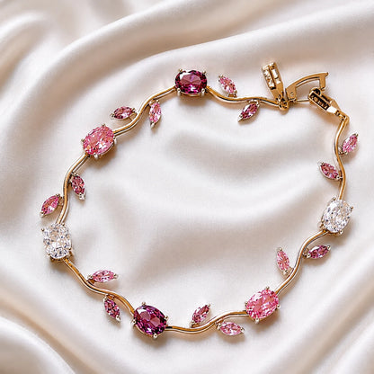 Gold bracelet with pink gemstones on a white fabric background