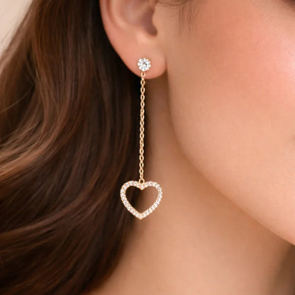 Close-up of a woman wearing a gold earring with a heart-shaped pendant.