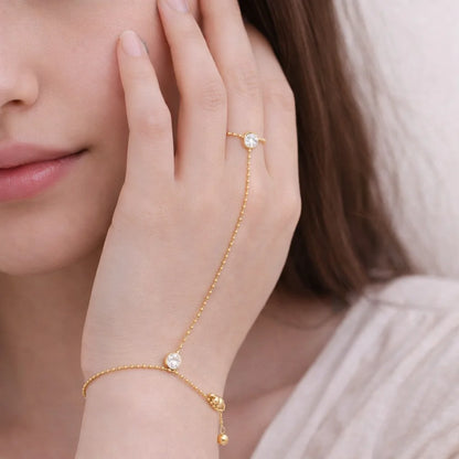 Close-up of a hand wearing a gold bracelet with small stones, held near the face.