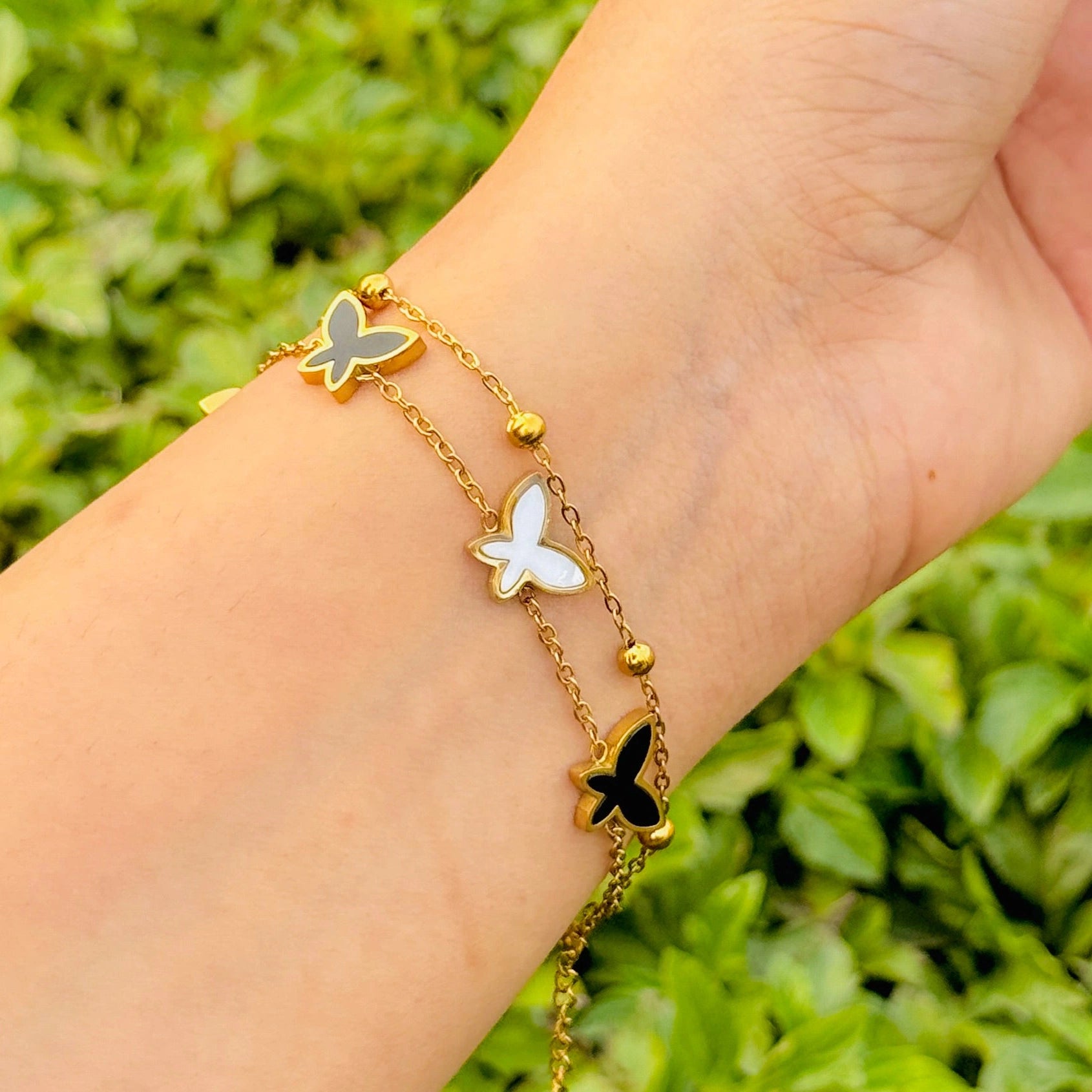 Butterfly bracelet on a wrist with a green leafy background