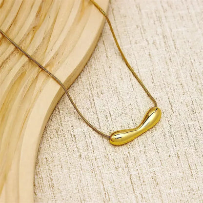 Gold necklace with a unique pendant on a textured beige surface