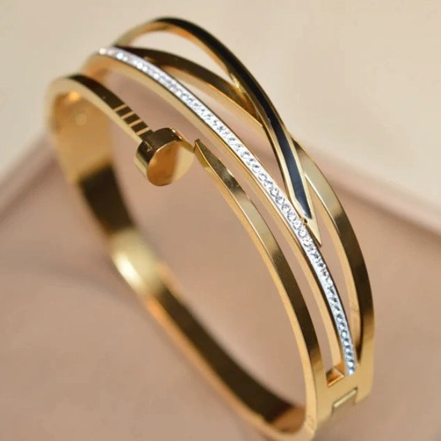 Gold bangles with a subtle design on a beige background