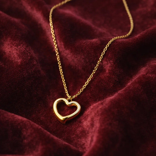 Gold heart-shaped pendant necklace on a burgundy fabric background