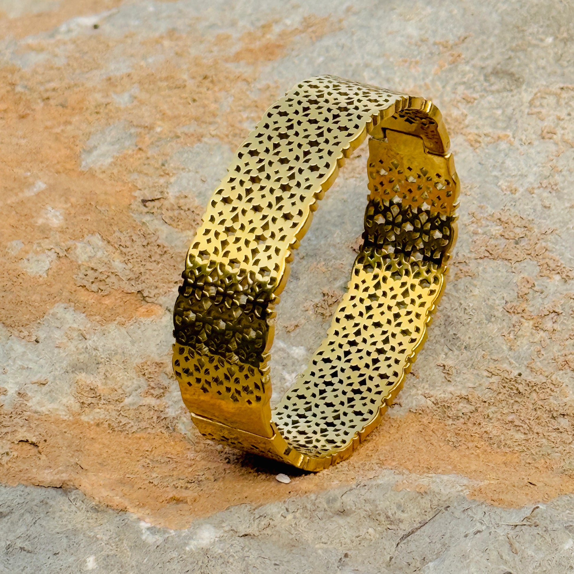 Gold bracelet with textured pattern on a stone surface