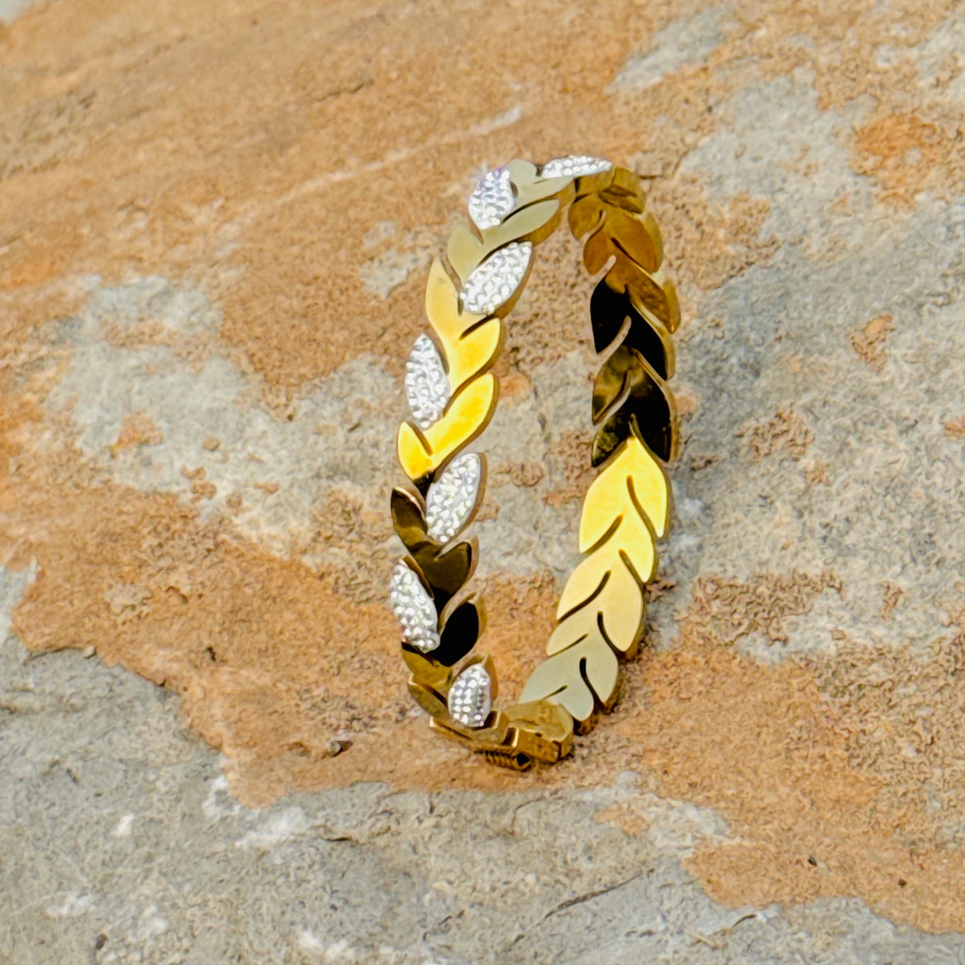 Gold and silver leaf-patterned bracelet on a stone surface