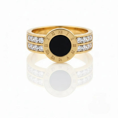 Gold ring with black center and diamond accents on a white background