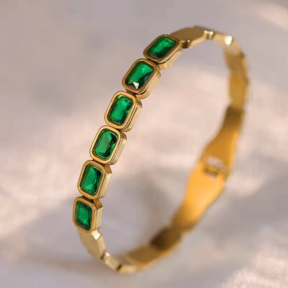 Gold bracelet with green gemstones on a soft background