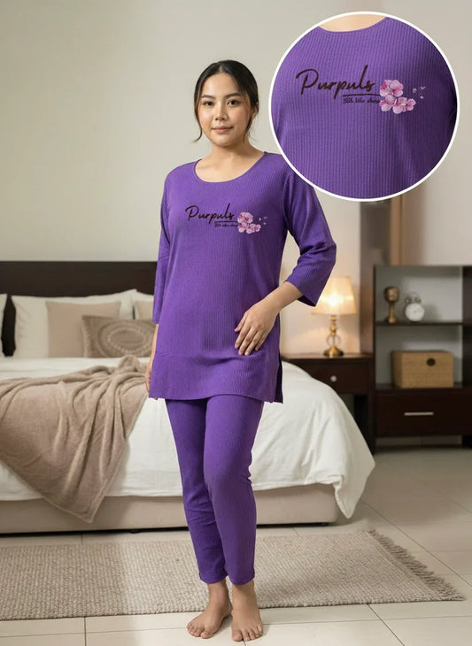 Woman in purple loungewear set with floral Purpul logo, standing in cozy bedroom