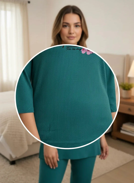 Woman wearing teal ribbed maternity lounge set in a cozy bedroom setting