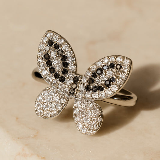 Butterfly-shaped ring with diamond accents on a beige background