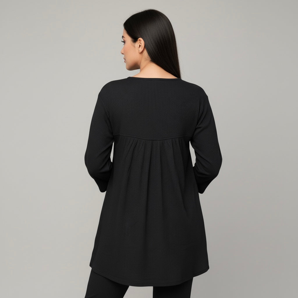 Woman wearing a black long-sleeve top against a gray background