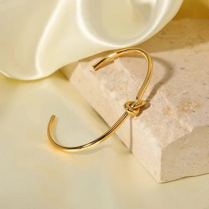 Gold bracelet with a knot design on a stone surface