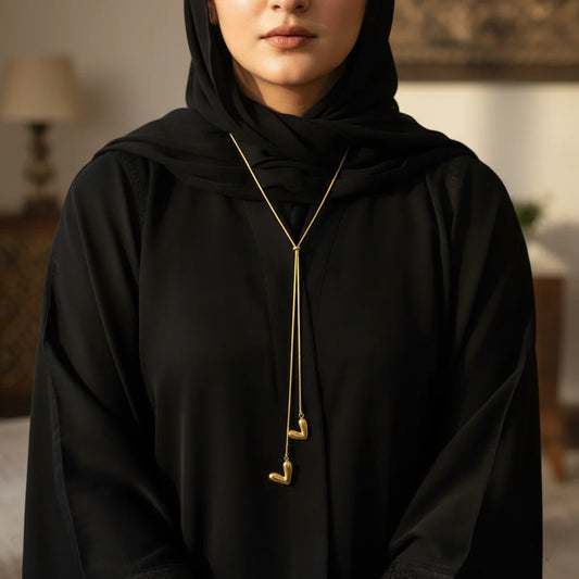 Person wearing a black garment with a gold necklace in an indoor setting