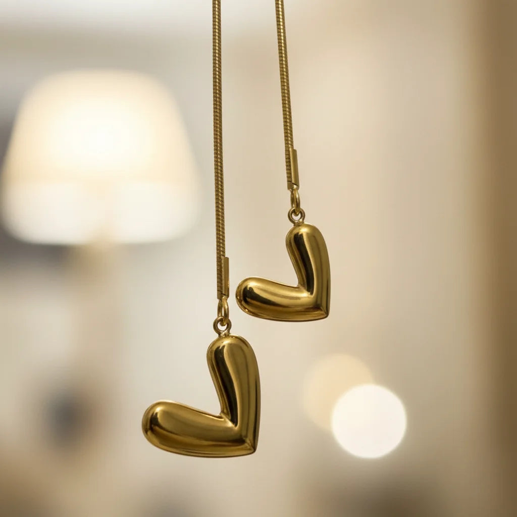 Gold heart-shaped earrings hanging against a blurred background