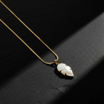 Necklace with a leaf-shaped pendant on a dark surface