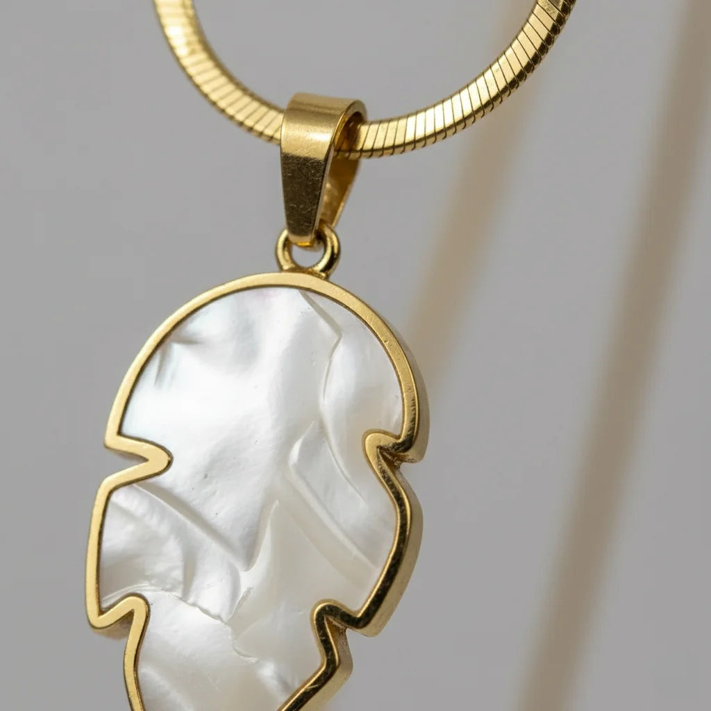 Gold necklace with a white pendant on a gray background