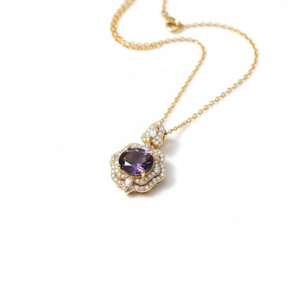 Gold necklace with a purple gemstone pendant on a white background