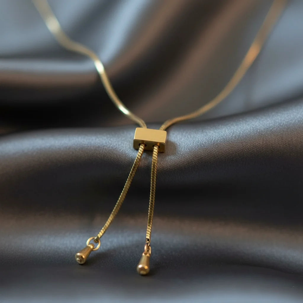 Gold necklace with a square clasp on a gray fabric background