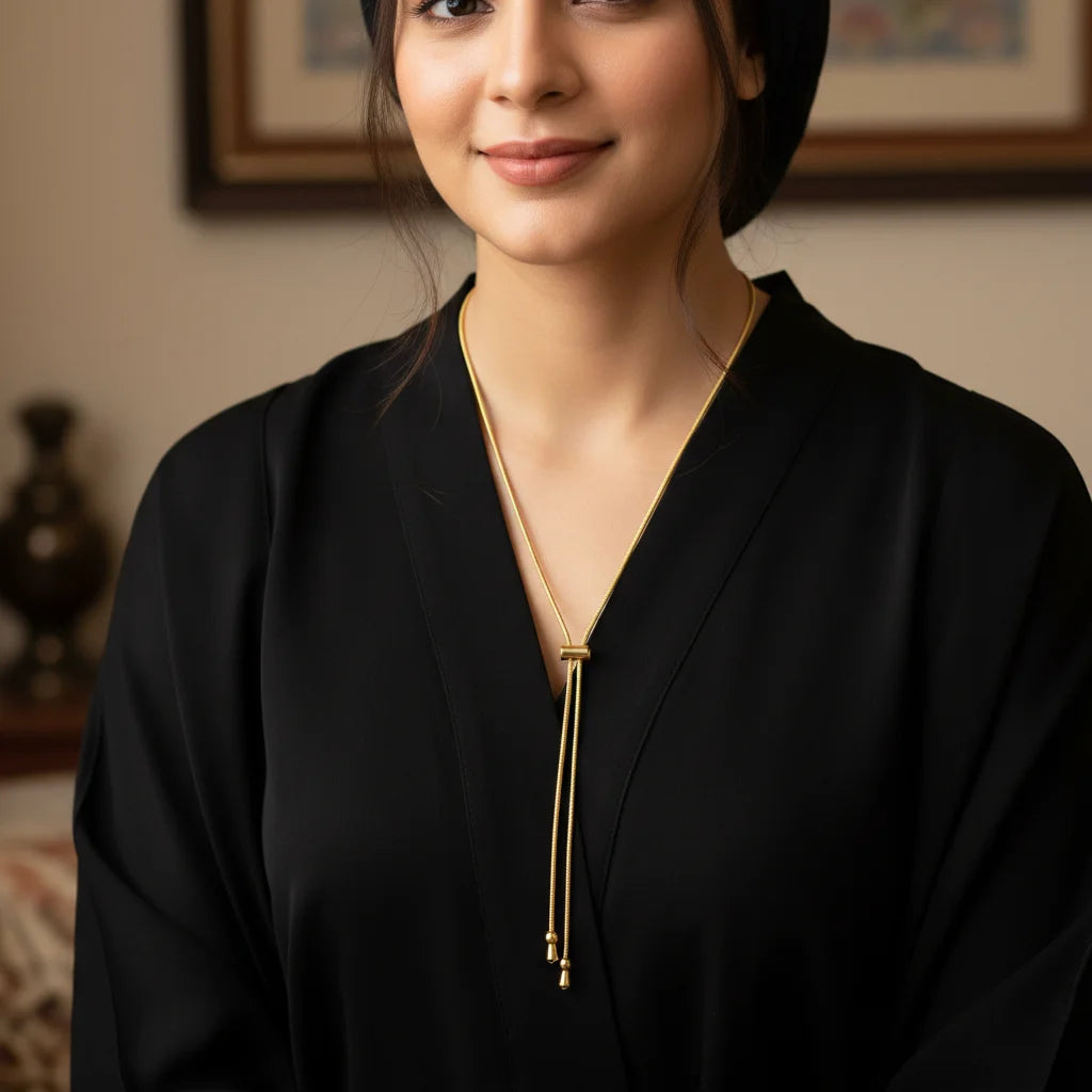Woman wearing a black outfit with a gold necklace indoors