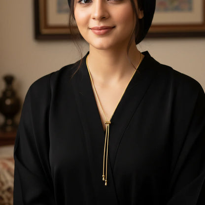 Woman wearing a black outfit with a gold necklace indoors