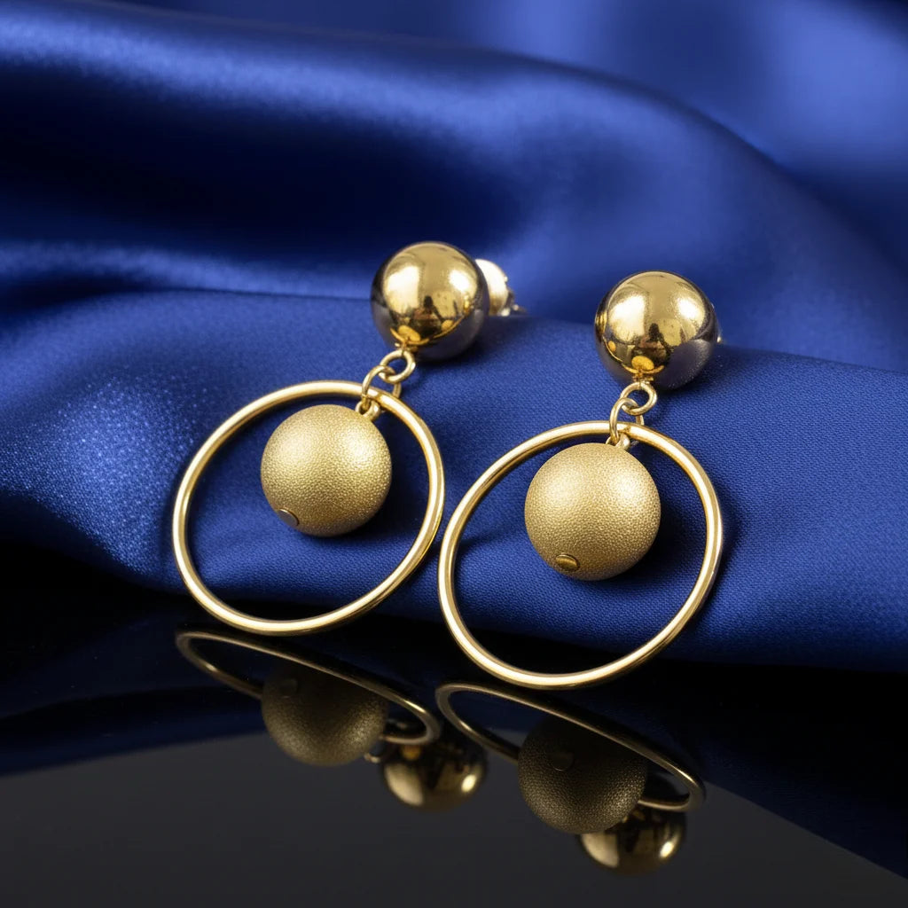 Gold earrings on a blue satin background