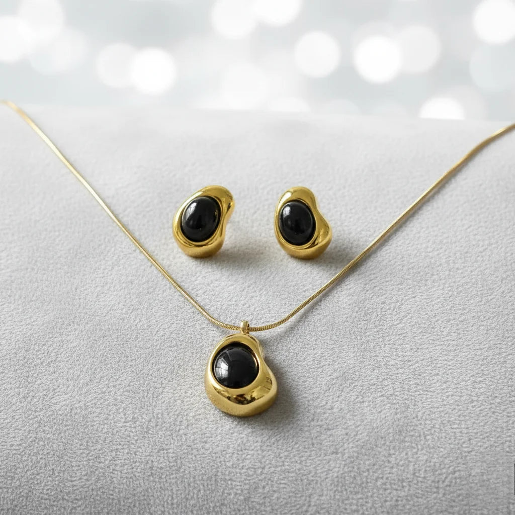 Gold necklace and earrings with black stones worn by a person