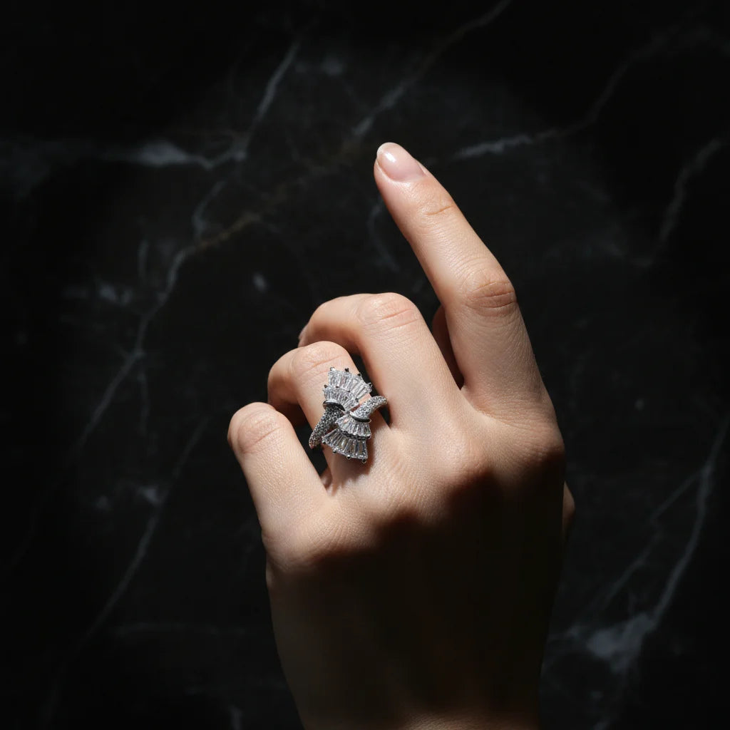 Hand wearing a silver ring with a dark background