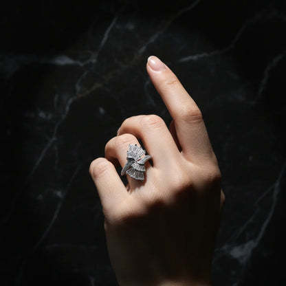 Hand wearing a silver ring with a dark background