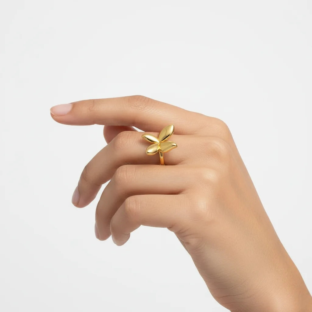 Gold butterfly ring on a hand against a light gray background