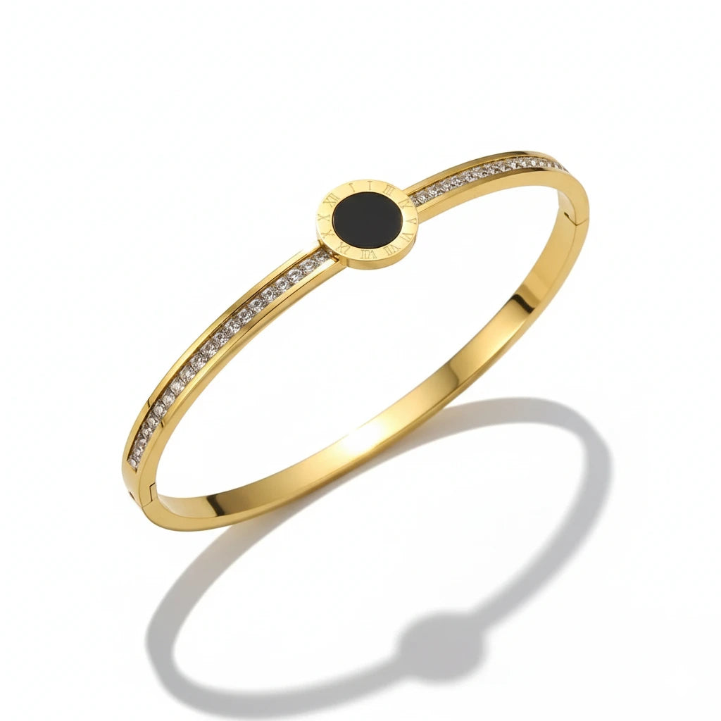 Gold bracelet with a black center stone on a white background