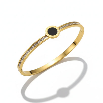 Gold bracelet with a black center stone on a white background