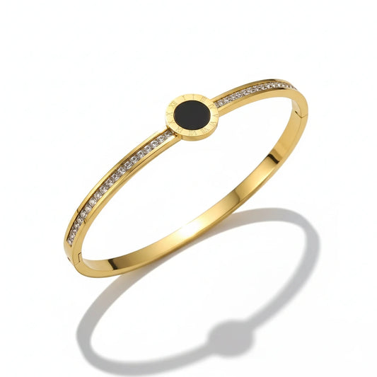 Gold bracelet with a black center stone on a white background