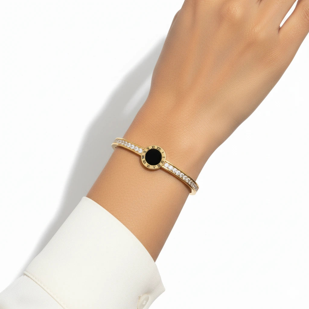 Gold bracelet with a black center stone on a white background
