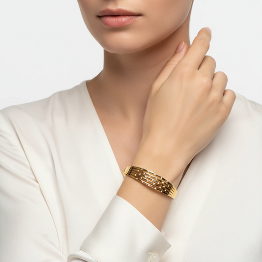 Gold bracelet on a person's wrist with a neutral background