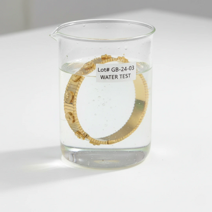 Gold bracelet in a beaker with water and 'LOT# GB-24-03 WATER TEST' label on a white background