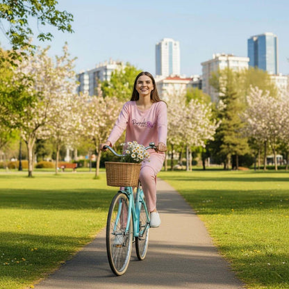 Woman in pink loungewear riding a bicycle with a flower basket in a city park
