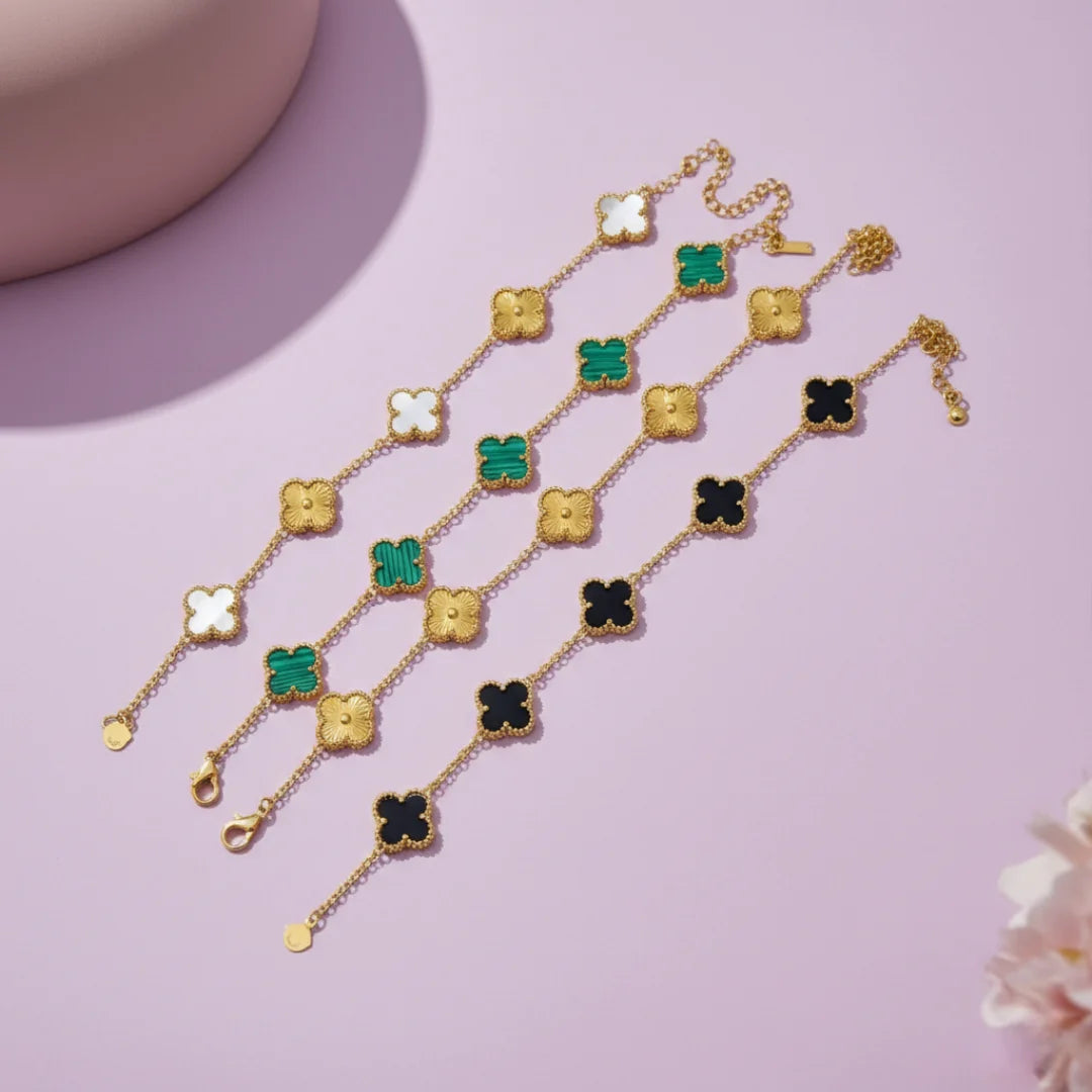 Gold necklace with clover-shaped charms on a pink background