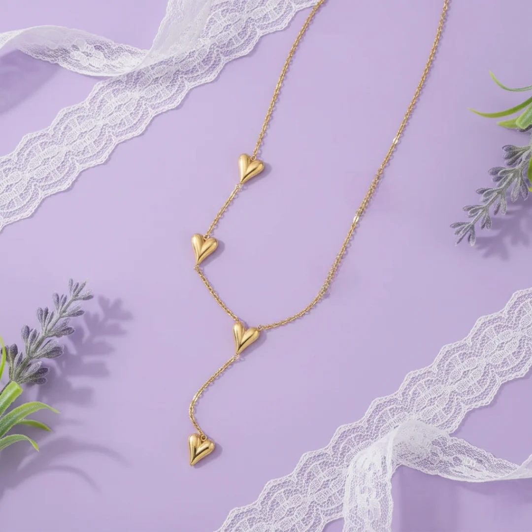 Gold heart-shaped necklace on a purple background with lace and greenery