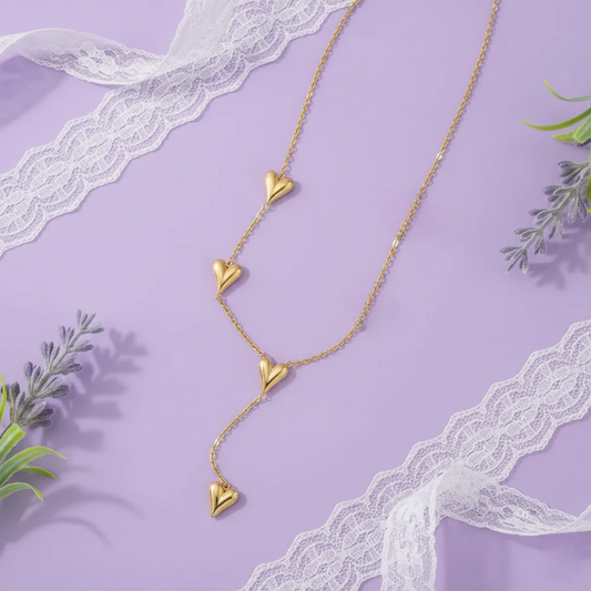Gold heart-shaped necklace on a purple background with lace and greenery