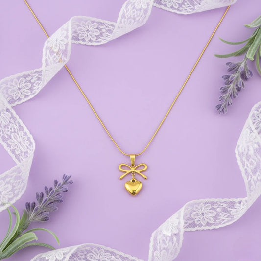 Gold necklace with a heart-shaped pendant on a purple background with lace and lavender.