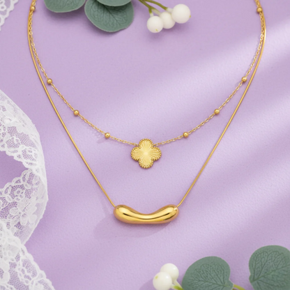 Gold necklace with floral pendant on a purple background
