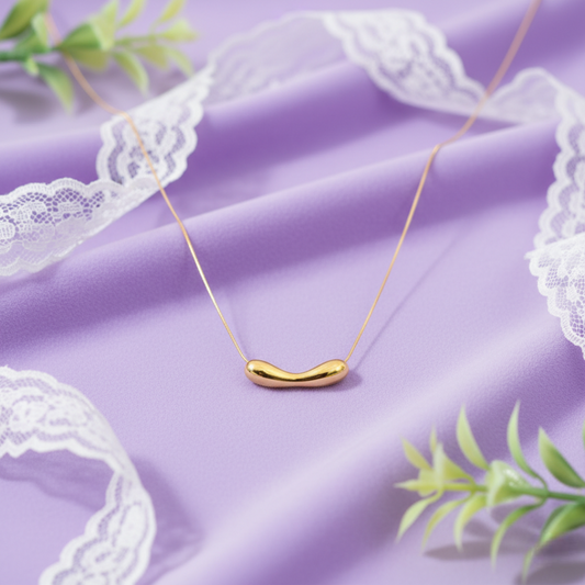 Gold necklace with a unique pendant on a purple fabric background