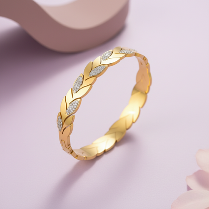 Gold bracelet with diamond accents on a pink background