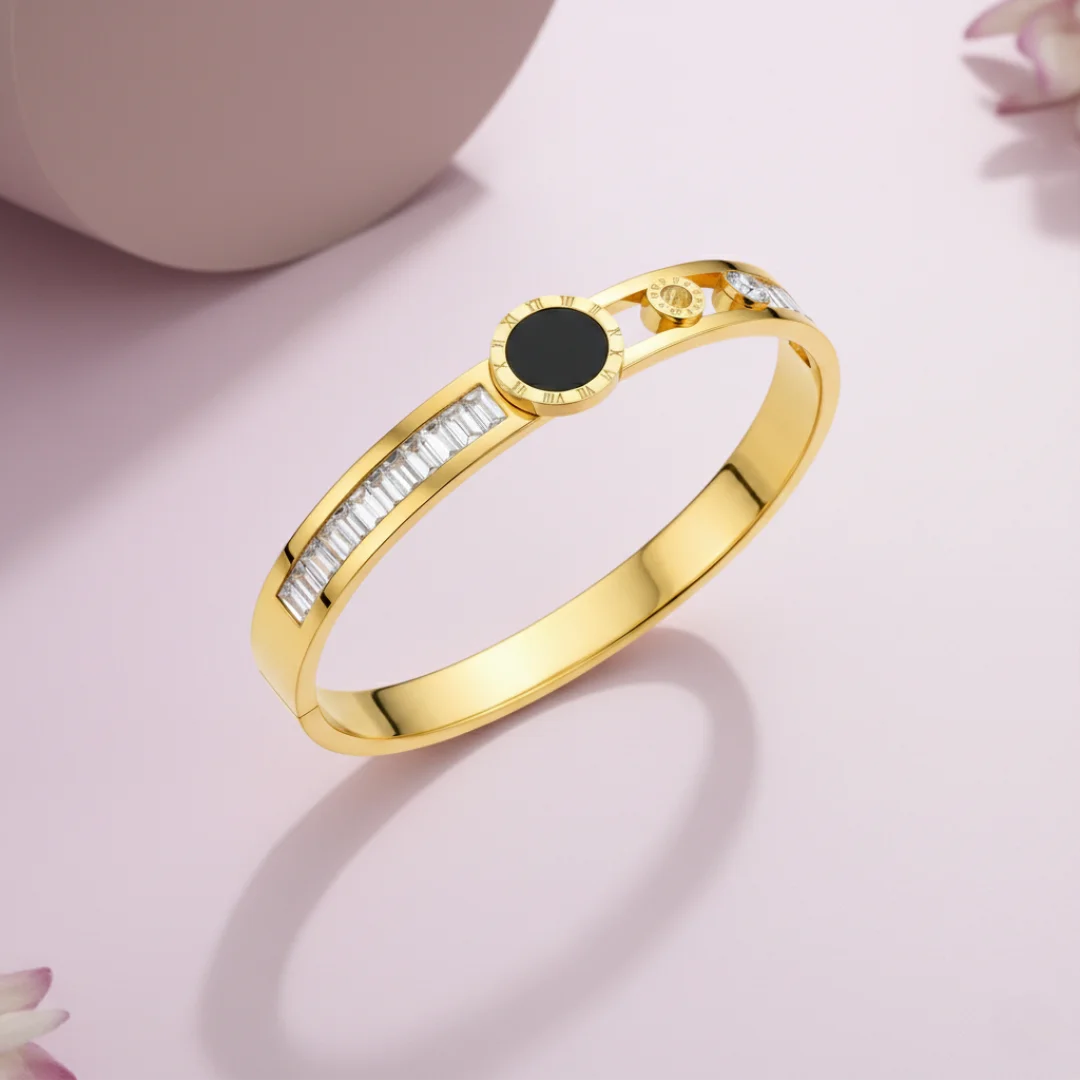 Gold bracelet with a black gemstone on a pink background