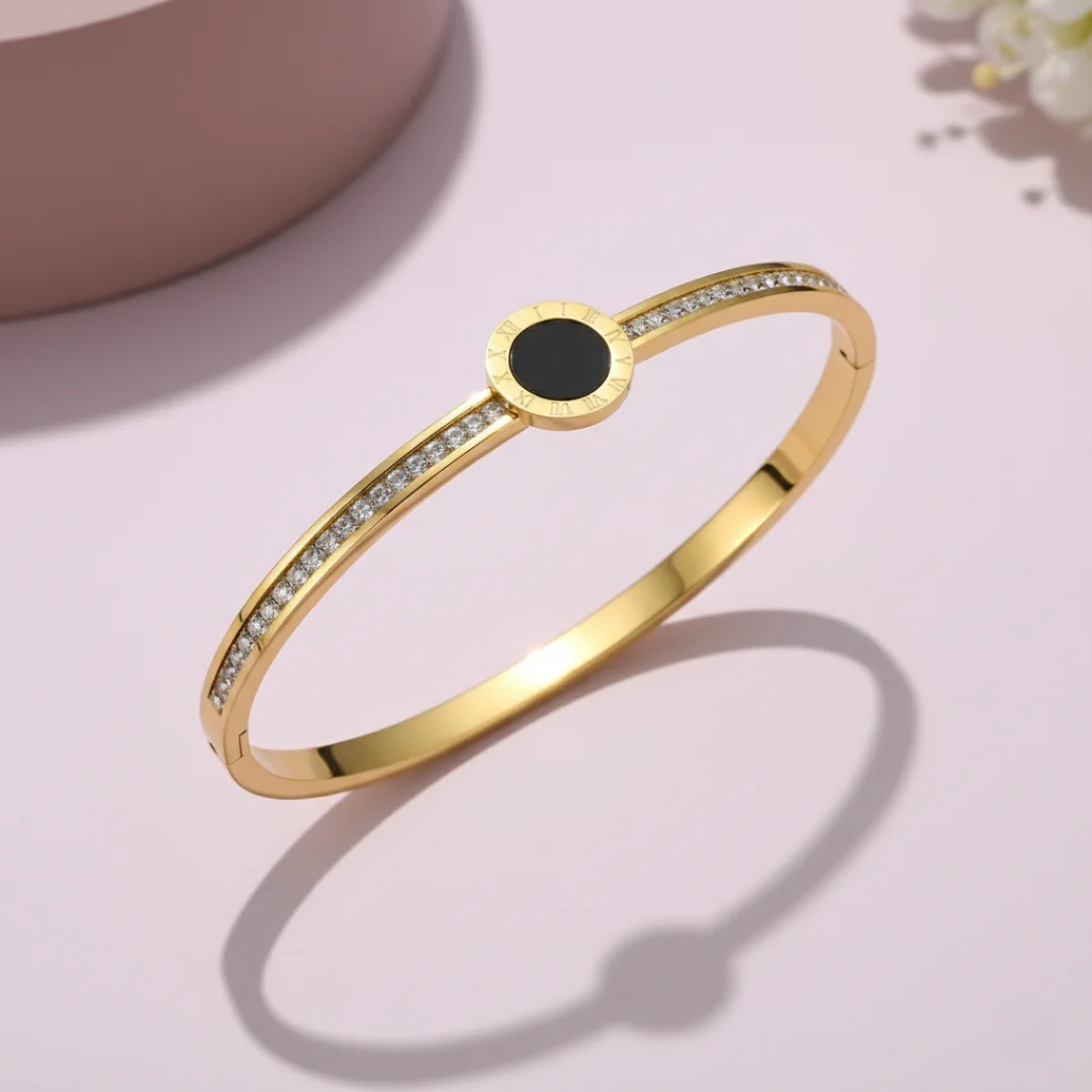 Gold bracelet with a black center stone on a light pink background