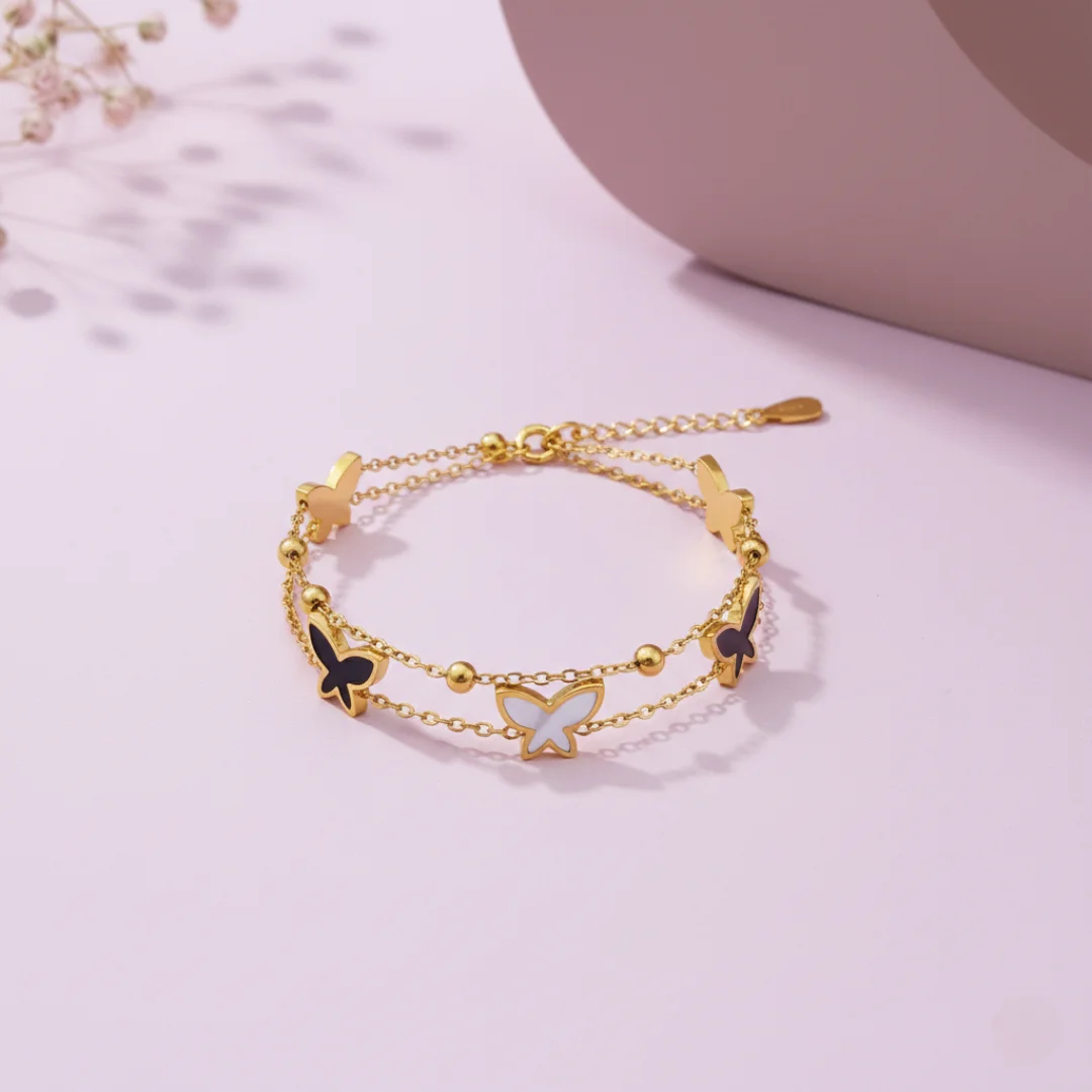 Gold bracelet with butterfly charms on a light pink background
