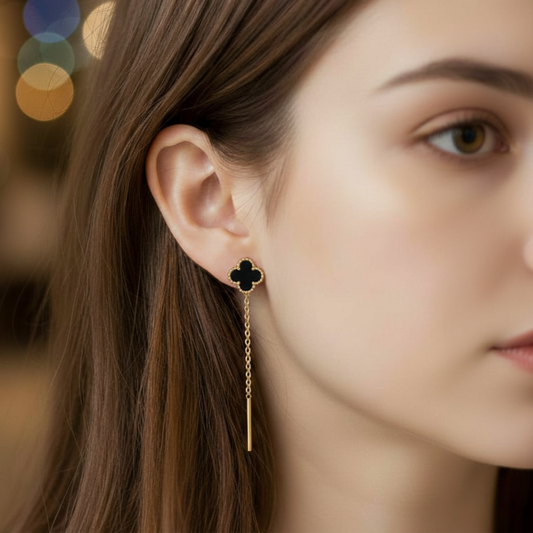 Close-up of a woman wearing a gold earring with a clover design.