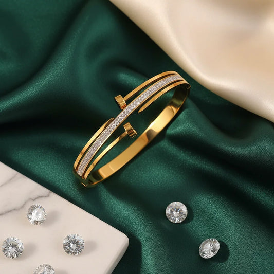 Gold bracelet with diamond accents on a green fabric background