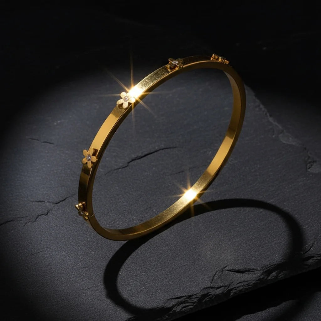 Gold bracelet with floral designs on a dark textured surface