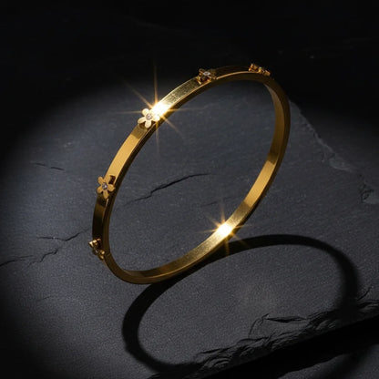 Gold bracelet with floral designs on a dark textured surface